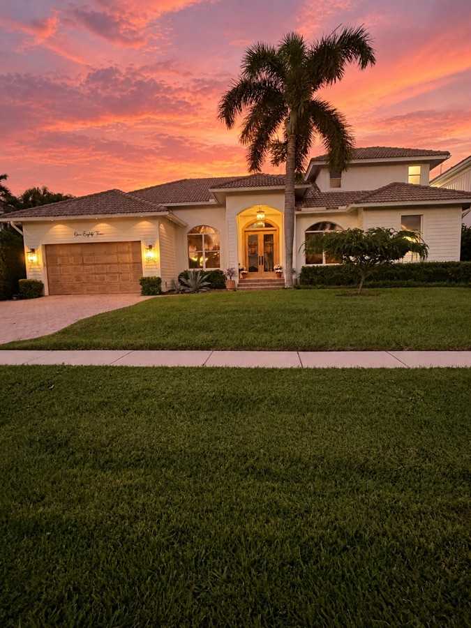 Front of 183 Geranium Court at sunset, with a palm out front and the two-car garage